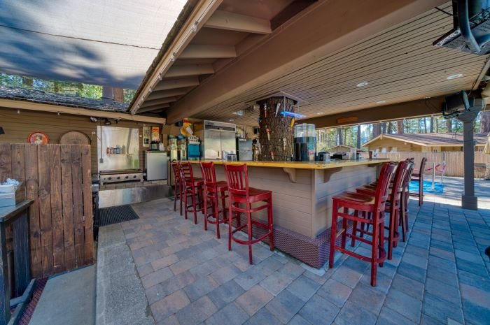 River Pines Resort — outdoor poolside bar with red stools under pine trees